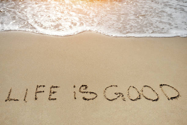 istock life in good written on sand beach - positive thinking concept 935523716