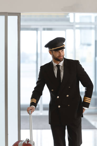 istock handsome young pilot with suitcase at departure area 935538090