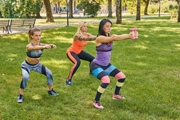 istock Three sporty women  doing squats in a park. 935538344
