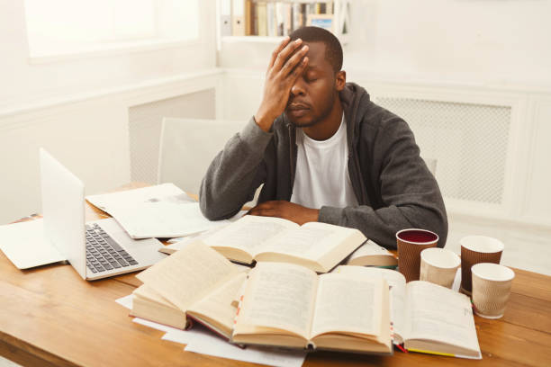 istock Black male student studying at table full of books 935542730