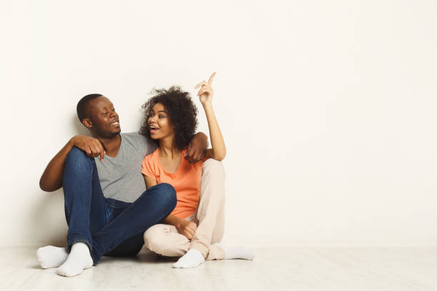 istock Black couple looking up sitting on floor 935543090