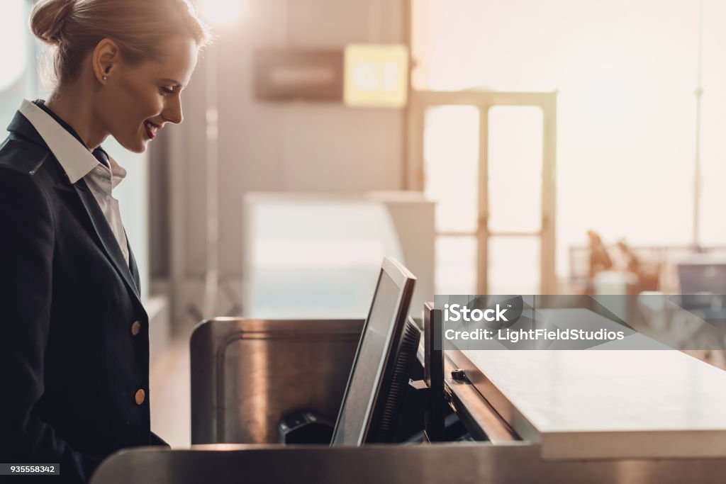 side view of attractive young airport worker at workplace at airport check in counter Airport Stock Photo