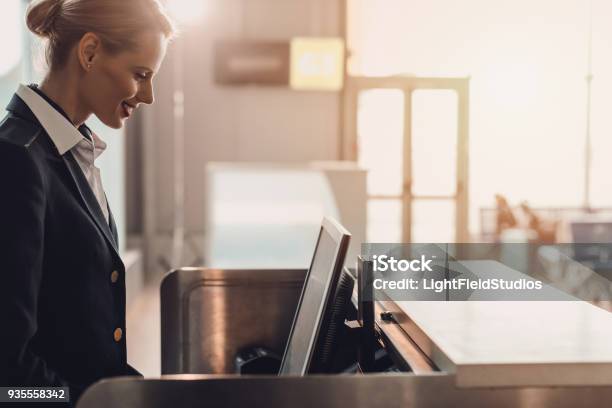 Side View Of Attractive Young Airport Worker At Workplace At Airport Check In Counter Stock Photo - Download Image Now