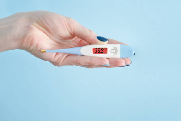 istock Electronic thermometer in a female hand. Elevated body temperature. Close up 935559694