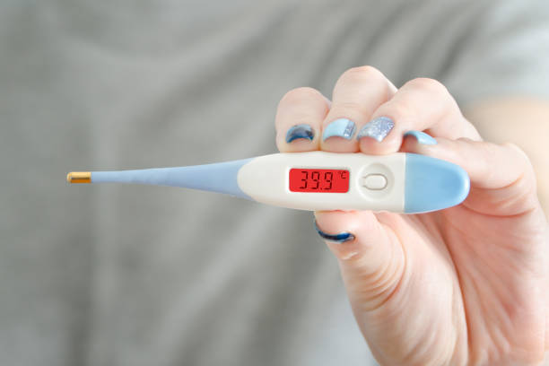 istock Electronic thermometer in a female hand. Elevated body temperature. Close up 935559736