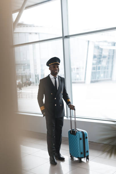 istock smiling young pilot in professional uniform with suitcase at airport 935564194