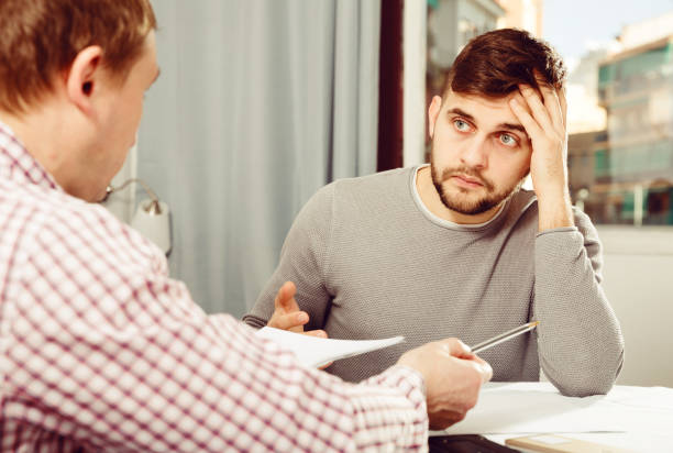 istock Man worriedly discussing documents with friend at home table 935566106