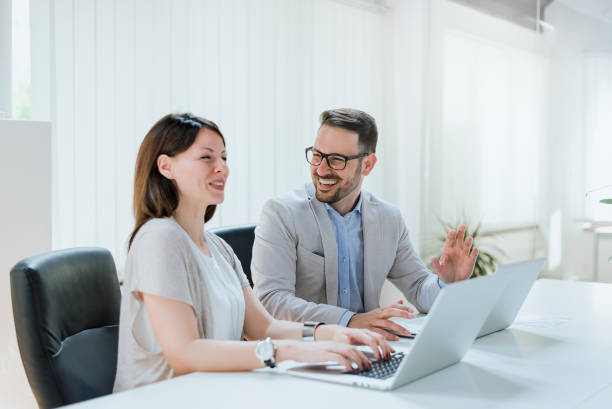 istock Couple of young colleagues at work, laughing 935566120