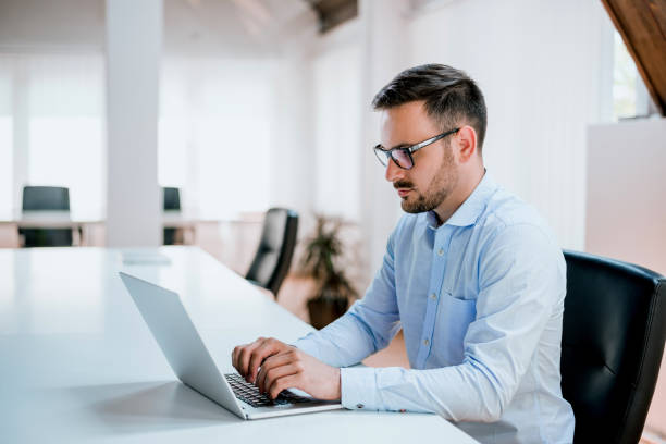 istock Businessman sitting at office desk working on laptop computer 935566152