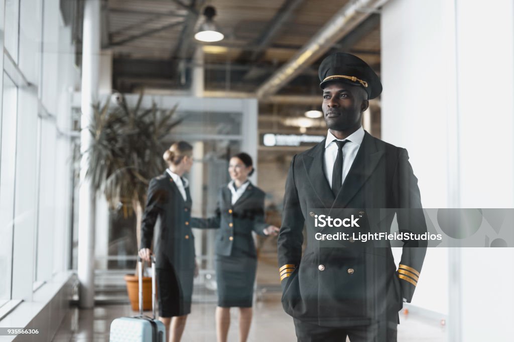 thoughtful young pilot in airport with stewardesses before flight Adult Stock Photo