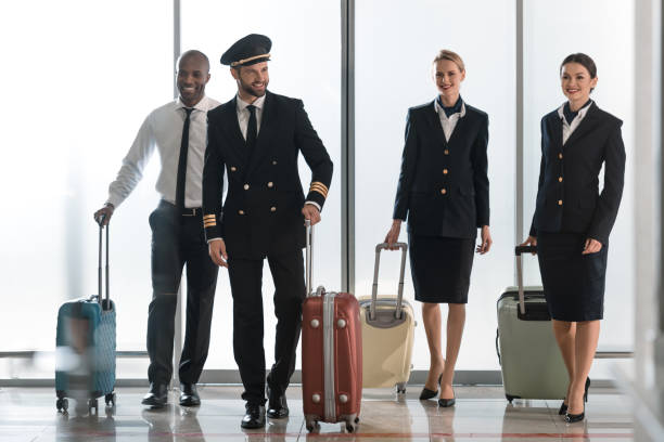 young aviation personnel team walking by airport loggy with suitcases young aviation personnel team walking by airport loggy with suitcases cabin crew stock pictures, royalty-free photos & images