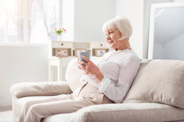 istock Pleasant elderly woman drinking tea on couch 935566936