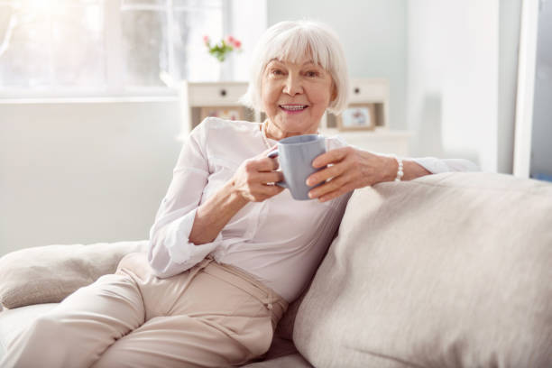 istock Upbeat senior woman drinking coffee on sofa 935567130