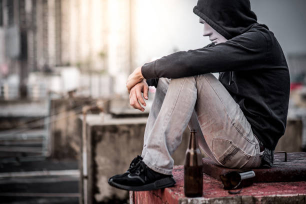 istock Mystery man in white mask sitting with empty and broken bottle in abandoned building 935571848