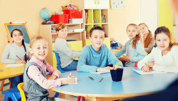 istock Diligent schoolkids sitting in classroom attentively listening t 935572184