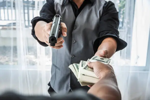 Photo of Gun and money in a hands. Bank robbery, Man carrying a gun to rob the money. To threaten with the gun man