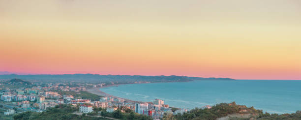 Aerial view to turquoise waters of Adriatic Sea close to Durres in central Albania. Golem zone. Green hills and sandy beach line. Sunset sky