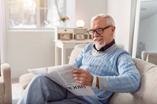 istock Upbeat senior man smiling while reading article in newspaper 935593808
