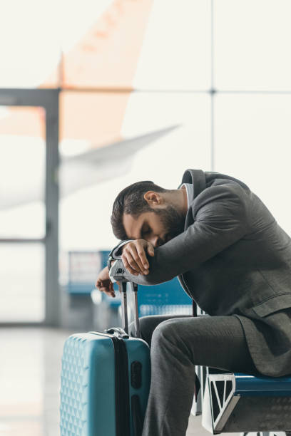 istock exhausted businessman sleeping at airport lobby while waiting for flight 935612710