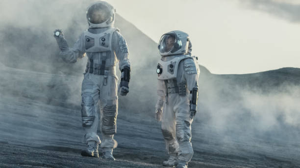 istock Two Astronauts Explore Rocky Alien Planet in the Day Time. Near Future and Technological Advance Brings Space Exploration, Travel, Colonization Concept. 935639658