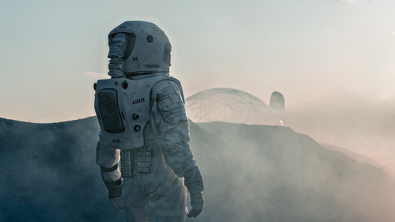 Tiro del astronauta en el planeta rojo mirando hacia su estación Base y de investigación. Junto a la futura primera misión tripulada a Marte, avance tecnológico trae la exploración espacial, colonización. photo