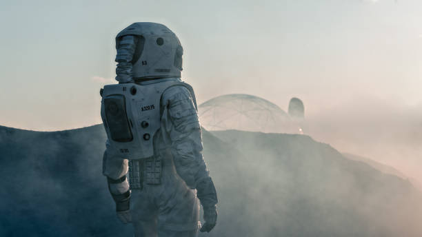 tiro do astronauta no planeta vermelho vendo em direção a estação de base/pesquisa. perto da futura primeira missão tripulada a marte, o avanço tecnológico traz exploração espacial, colonização. - colonization - fotografias e filmes do acervo