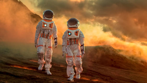 istock Two Astronauts Wearing Space Suits Walk Exploring Mars/ Red Planet. Space Travel, Exploration and Colonization Concept. 935639976