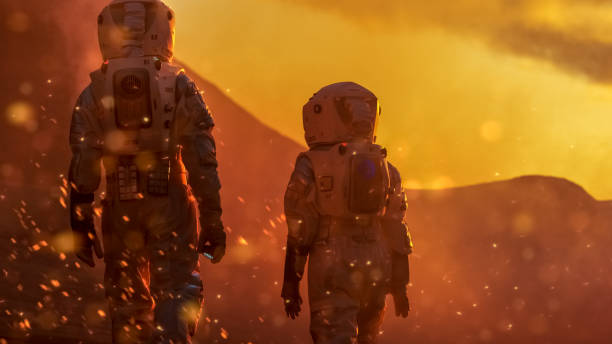 istock Two Astronauts Wearing Space Suits Exploring High Temperature Venus/ Red Planet During Fire Storm/ Sunset. Space Travel and Solar System Colonization Concept. 935640012
