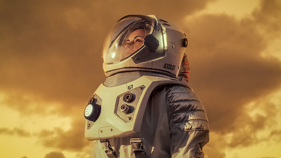 Foto de mujer astronauta en el traje espacial, mirando a su alrededor planeta alienígena. Planeta rojo y el naranja Similar a Marte. Tecnologías avanzadas, recorrido de espacio, concepto de colonización. photo