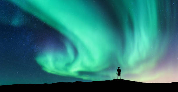 Aurora borealis and silhouette of standing man Aurora borealis and silhouette of standing man. Lofoten islands, Norway. Aurora and happy man. Sky with stars and green polar lights. Night landscape with aurora and people. Concept. Nature background aurora borealis stock pictures, royalty-free photos & images