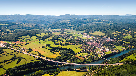 Aerial view of beautiful french countryside with elevated highway small village and beginning of Alps mountains in background