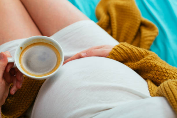 Pregnant woman Pregnant woman drinking coffee. Aerial close up view. pregnancy and coffee stock pictures, royalty-free photos & images