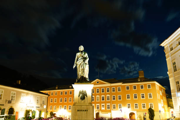 statue mozart in square at night illumimnated and golden in color in old town. - editorial built structure fountain town square imagens e fotografias de stock