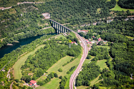 Aerial view of curved french railroad track with Ain river and stone viaduct of Cize-Bolozon in Bugey mountains