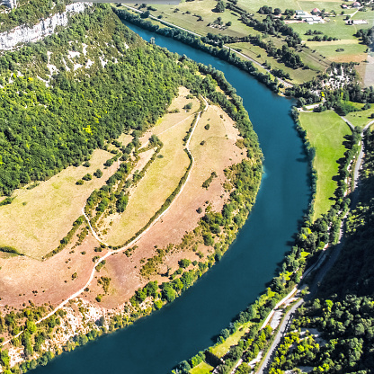 Color photography aerial view of french Ain river valley curved in horseshoe shape in Bugey mountains. This image was taken by airplane in summer, during a bright sunny day with green trees, near Jura border in Auvergne-Rhone-Alpes region in France (Europe).