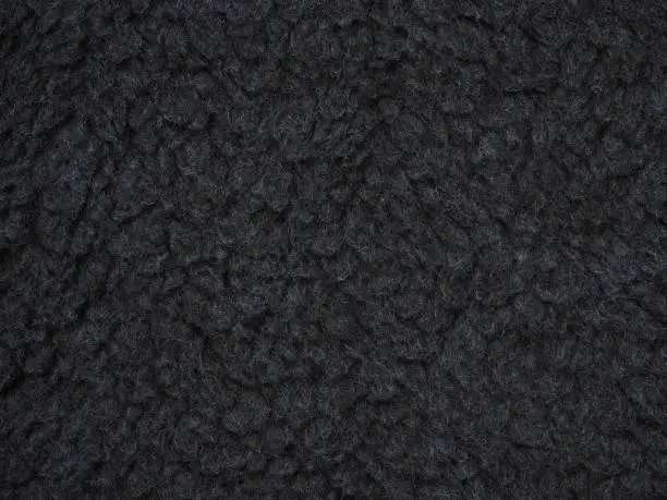 Close-up dark gray wool texture. Knitwear, background of oxford gray fluffy woolen. Fleece sheep