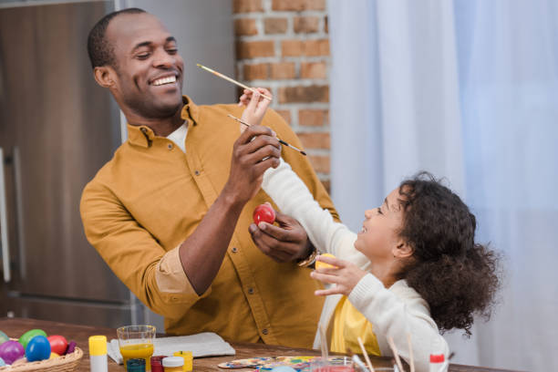 афро-американских отец и дочь весело во время рисования пасхальных яиц - vacations two generation family holiday easter стоковые фото и изображения