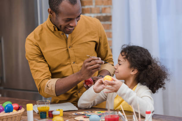 istock african american father painting daughter nose while painting easter eggs 935659916