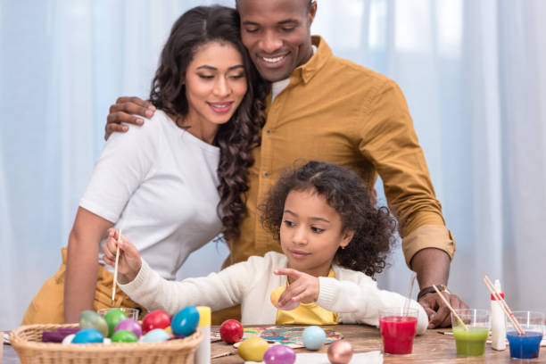 istock african american parents looking how daughter painting easter eggs 935670766