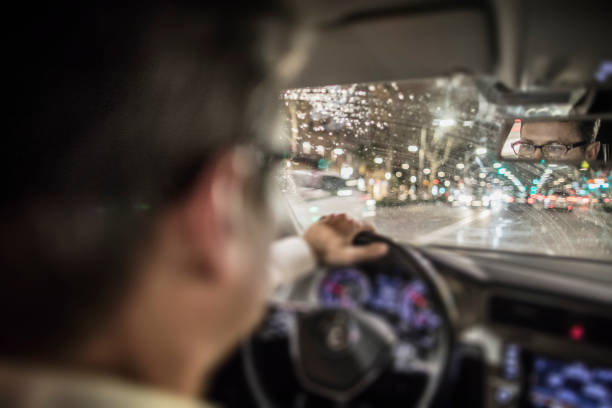 homme au volant de voitures pendant la nuit dans la ville - night wet road street photos et images de collection