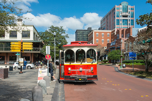 People exiting a street car on a sunny day in the busy and picturesque downtown of Tallahassee, the capital city of the southern US state of Florida.