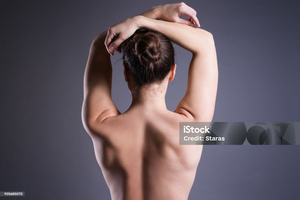 Slim topless woman on gray background, beauty female back Slim topless woman on gray background, beauty female back, rear, view Back Stock Photo