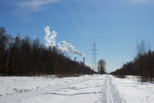 Thermal power station and power lines in the forest, winter landscape, snowy winter