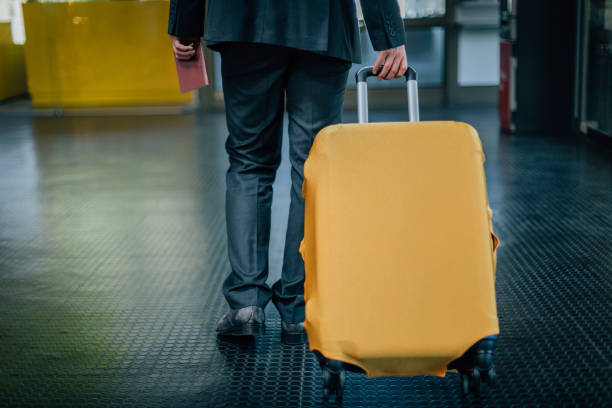 istock Businessman pulling suitcase at the airport and holding passport 935690136