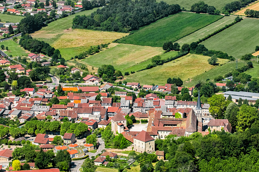 Color photography aerial view of french village, Ambronay city in Ain, Auvergne-Rhone-Alpes region France (Europe), in Bugey mountains in Alps. Countryside in summer season with green nature and red roof from houses and buildings from the town, with famous abbey and church made of stone.