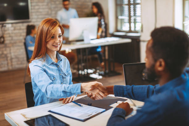 Mujer joven firma contratos y apretón de manos con un gestor de - foto de stock