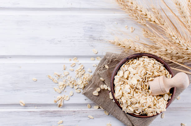 istock Oat flakes  in ceramic bowl and wooden spoon and spikelets 935694714