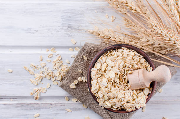 istock Oat flakes  in ceramic bowl and wooden spoon and spikelets 935695014