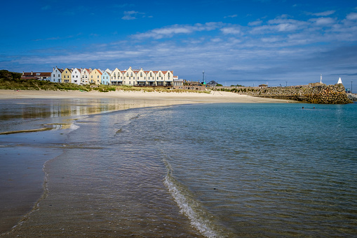 Row of houses and a hotel, reflected in the water at Braye Beach, Alderney, Guernsey, Channel Islands