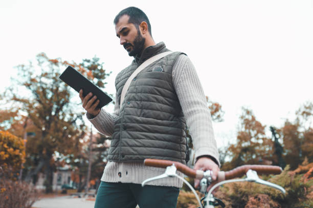istock Handsome man with a bicycle using digital tablet outdoors on a sunny day 935695600